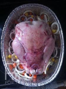 thankgiving turkey in a roasting pan with carrots onion potato