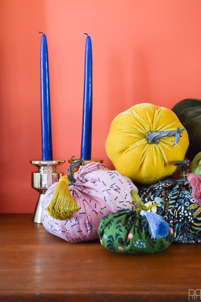 colourful fabric pumpkins against orange wall with blue candles