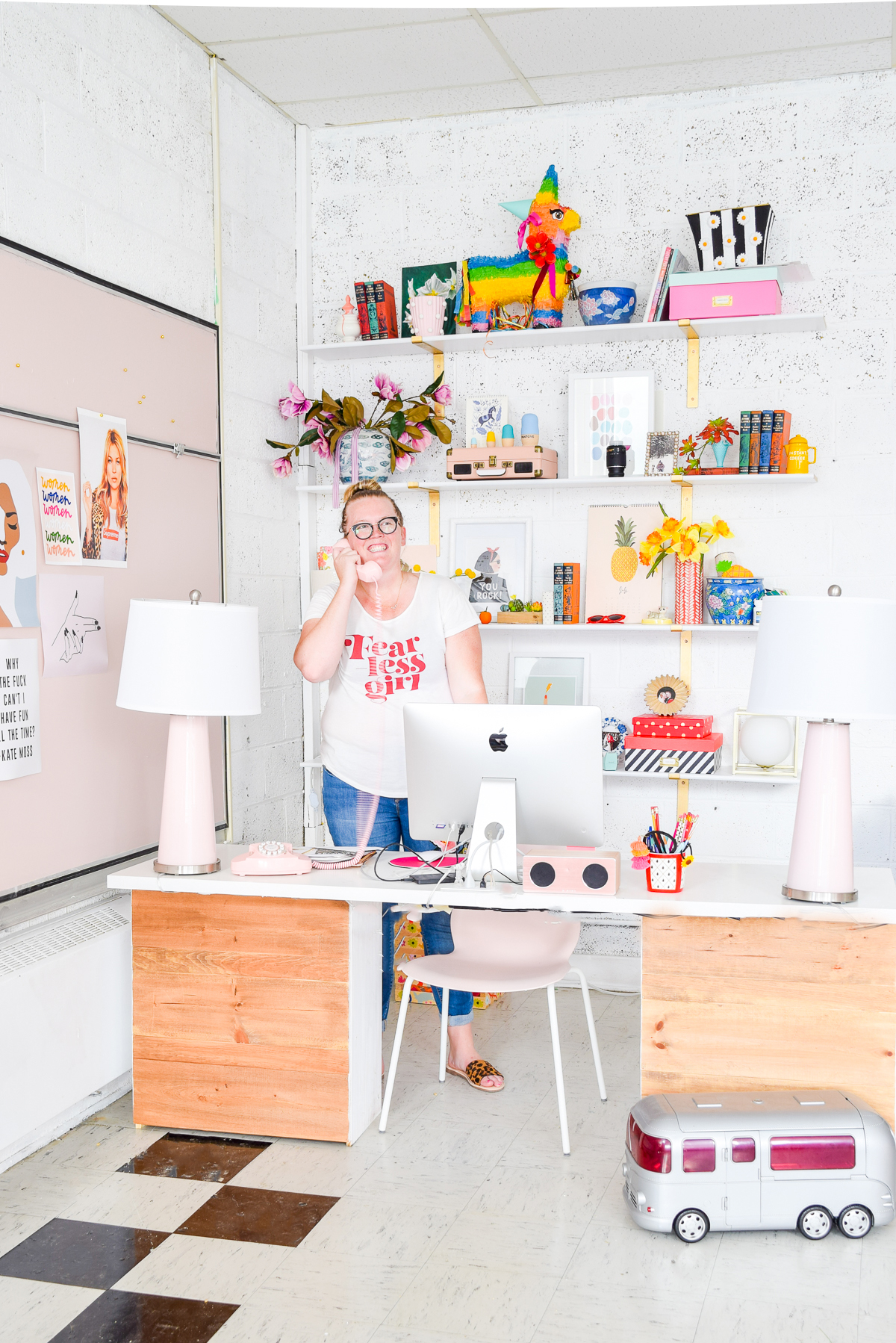 Who would have thought that gold shelf brackets would have kicked-off a pink & gold office revamp? Full of bright colours, gold, playful touches and accessories from women owned stores, what's not to love? woman on the phone standing behind desk