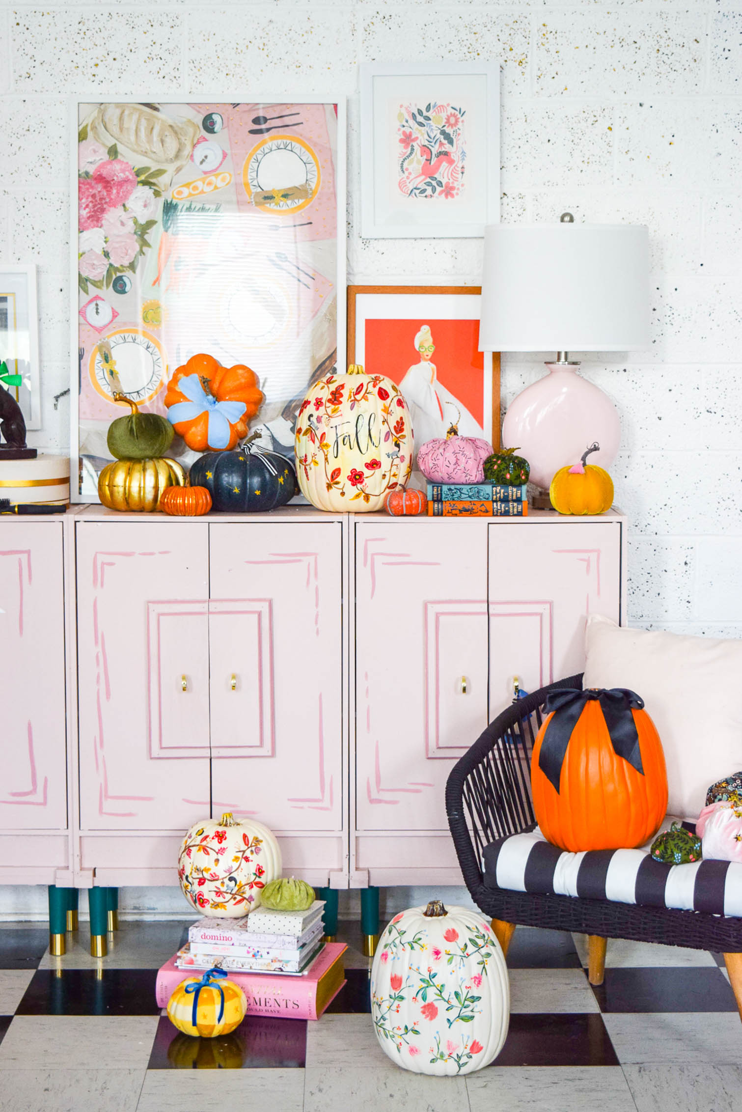 painted pumpkin display on a pink dresser with art
