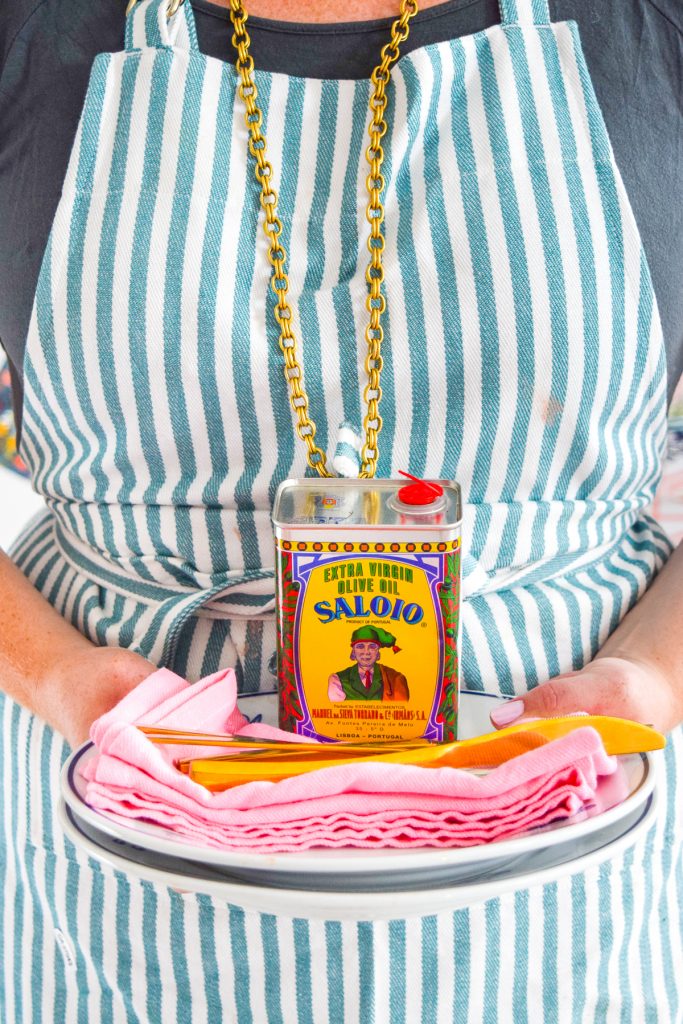 woman in apron holding plates with olive oil
