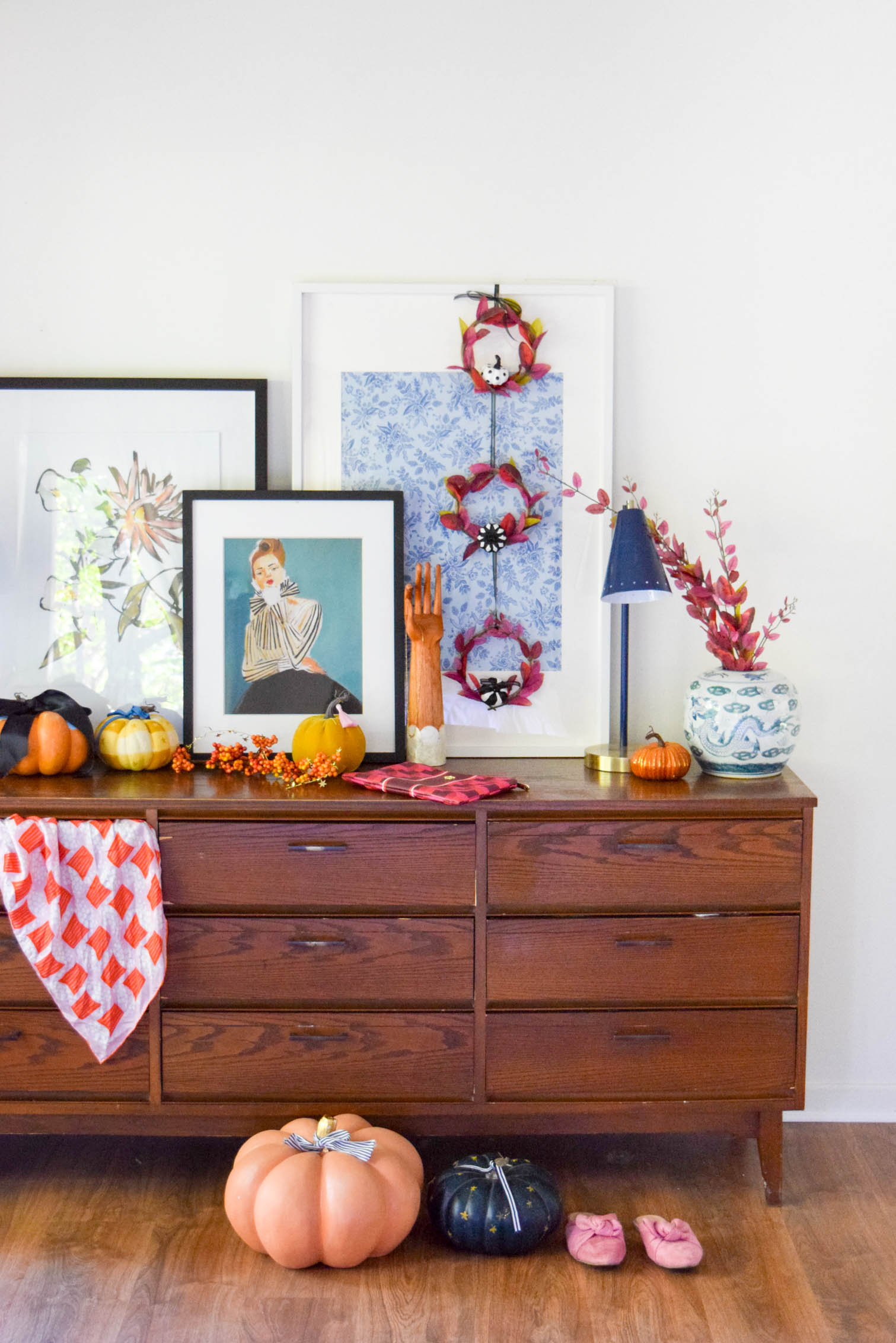 wide shot of a dresser decorated for fall with pumpkins and mini purple fall wreaths