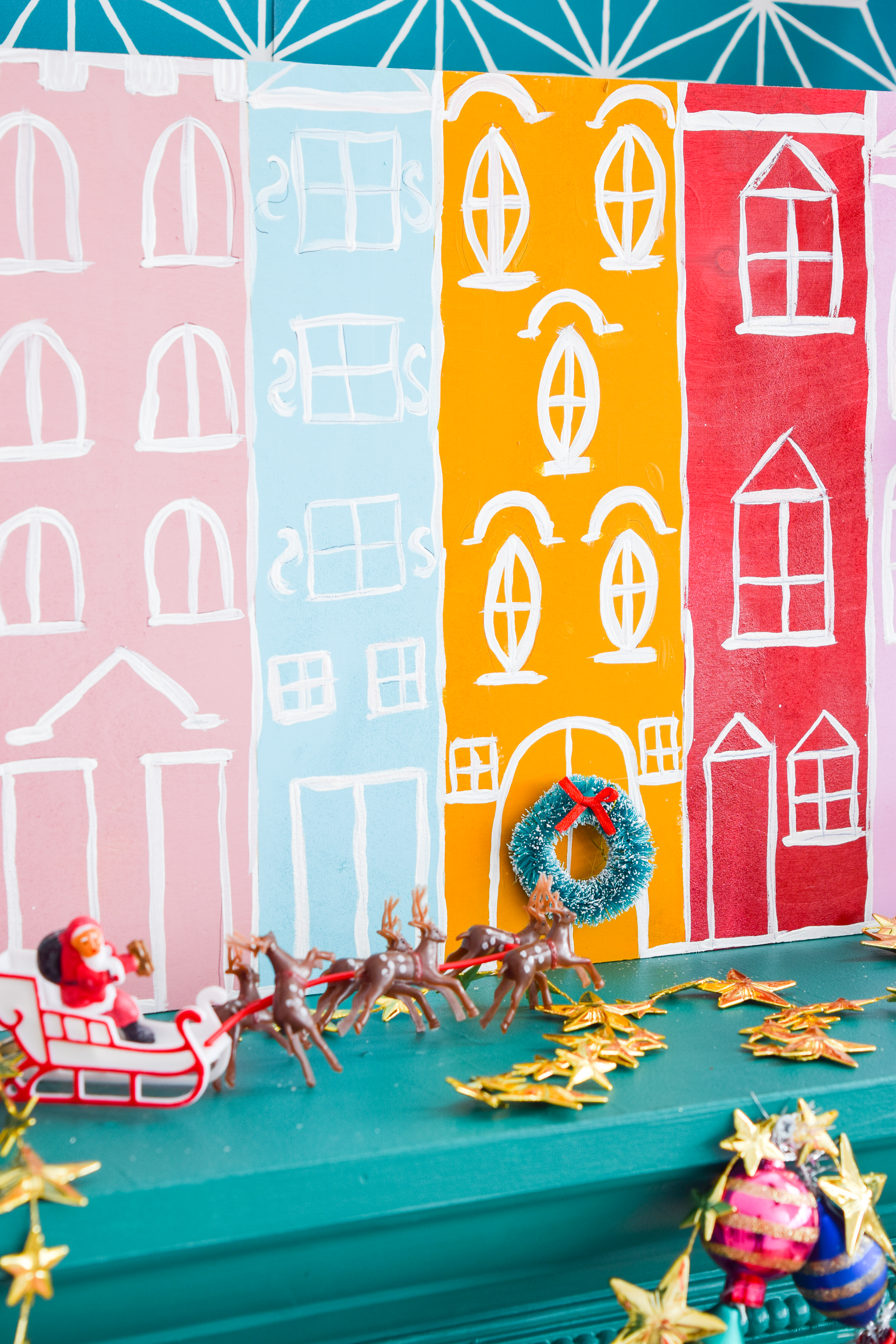 A painted Christmas village is all you need to bring a dose of seasonal cheer (and colour!) to your Christmas mantel, sideboard, or console table! Grab your Americana Acrylic Paints & Dazzling Metallics to get started. #christmascraft #christmasvillage 