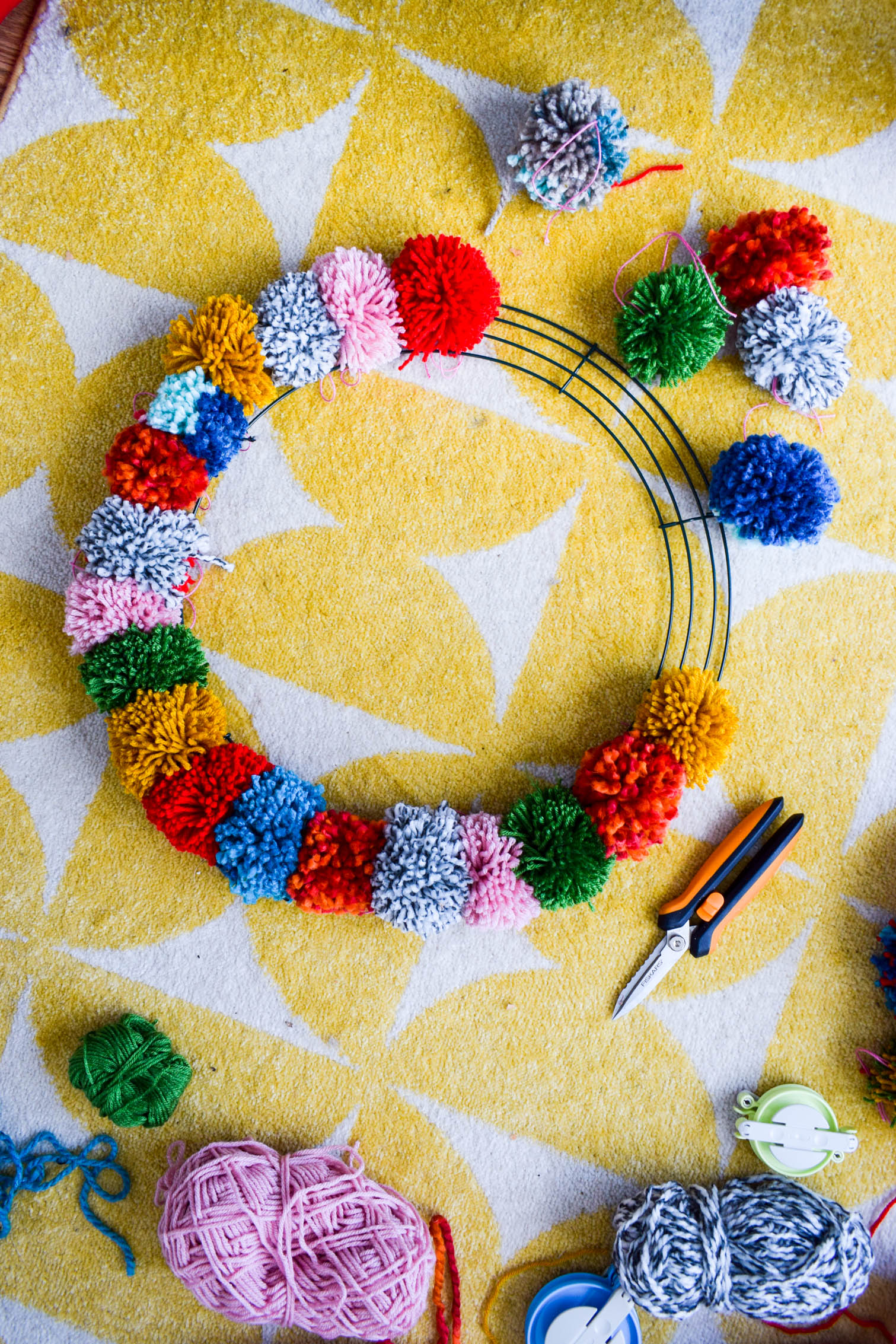 Make your own pom pom wreath this holiday season, and add a bold statement to your decor. This wreath is easy to make and a lot of fun to put together.