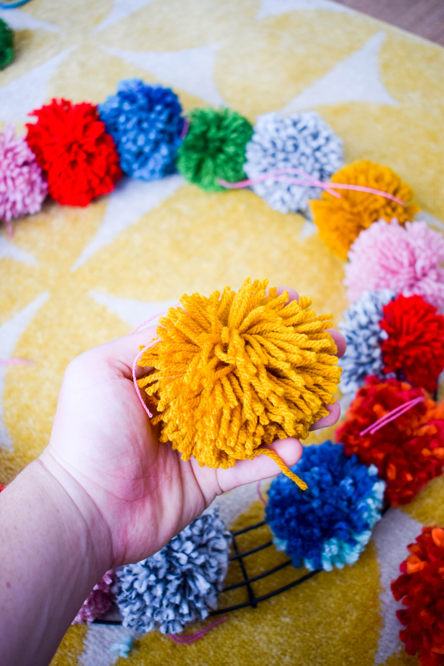 Make your own pom pom wreath this holiday season, and add a bold statement to your decor. This wreath is easy to make and a lot of fun to put together.