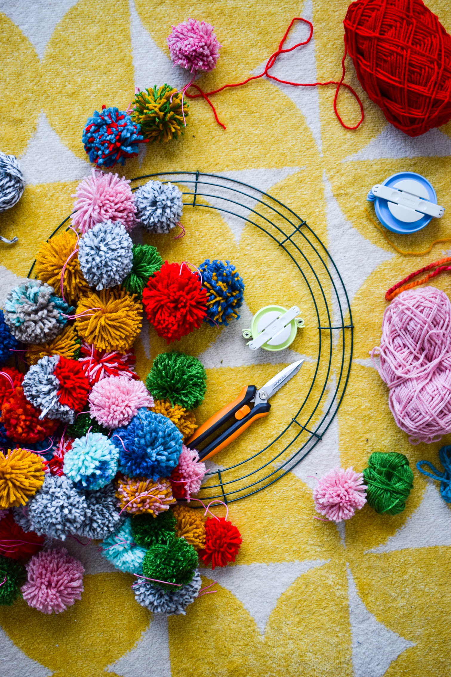 Make your own pom pom wreath this holiday season, and add a bold statement to your decor. This wreath is easy to make and a lot of fun to put together.